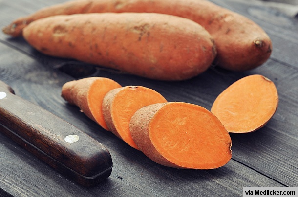 Raw sweet potatoes on wooden board