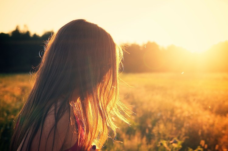 Girl with shiny hair on sunlit summer field